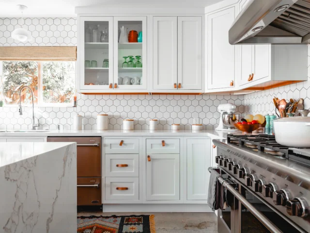 Bright kitchen with white cabinets, hexagonal wall tiles and a marble island