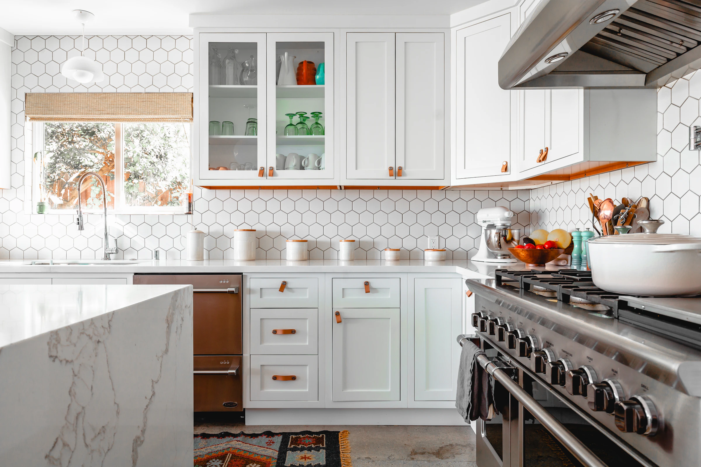 Bright kitchen with white cabinets, hexagonal wall tiles and a marble island
