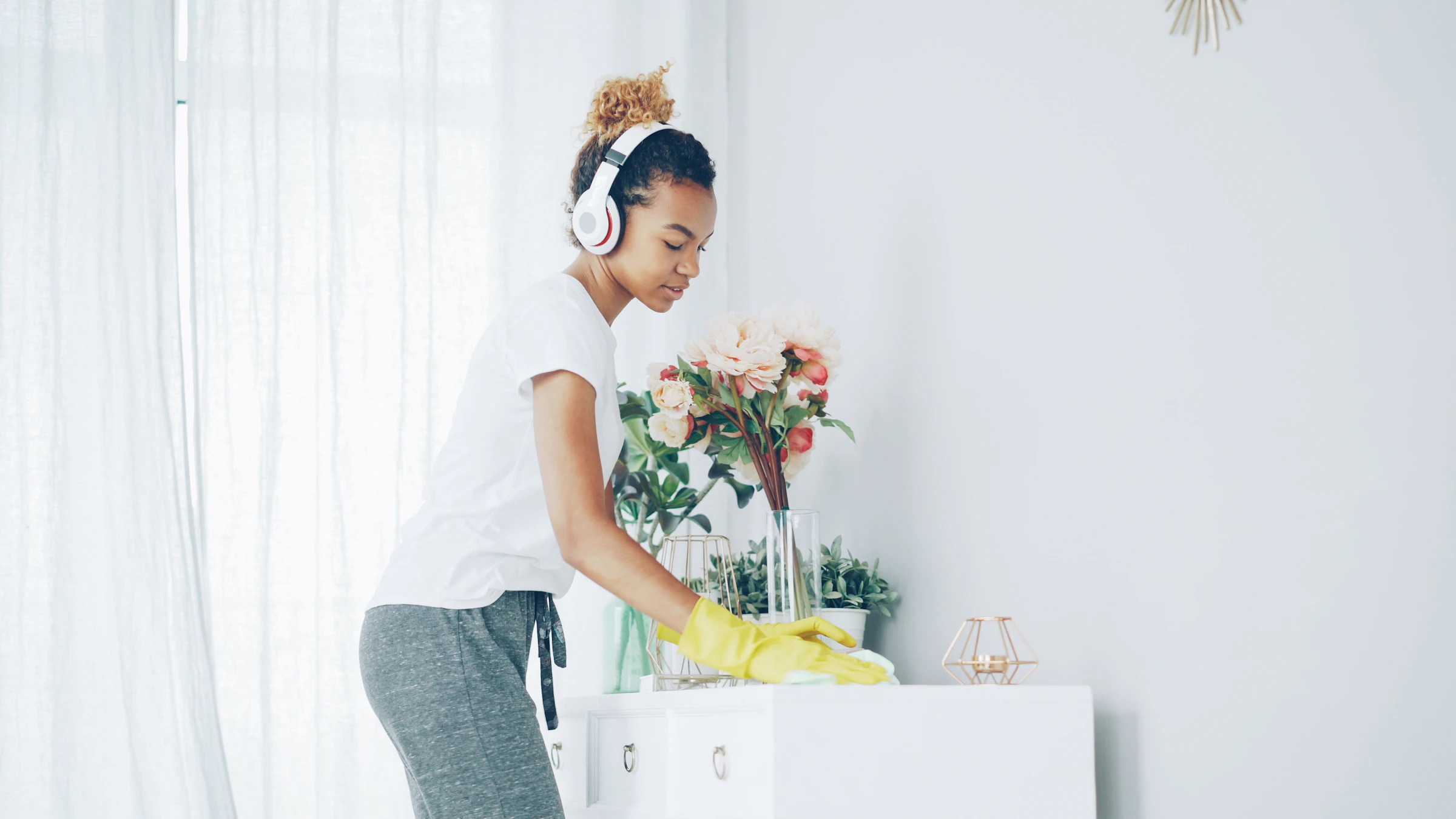 Cleaner dusting shelves in a bright home
