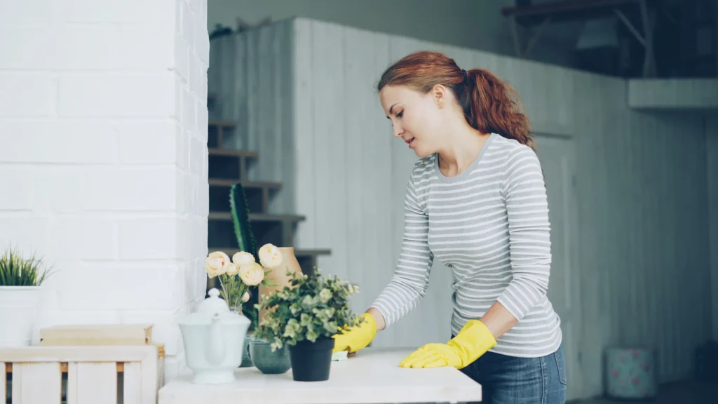 Cleaner in yellow gloves wiping a dining table
