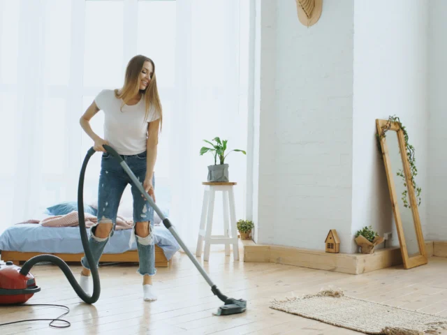 Cleaner vacuuming a bright living room
