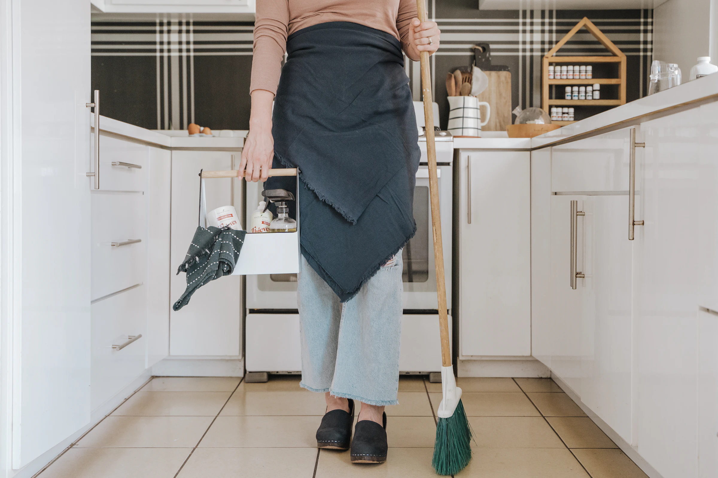 Cleaner with a broom in an empty rental kitchen