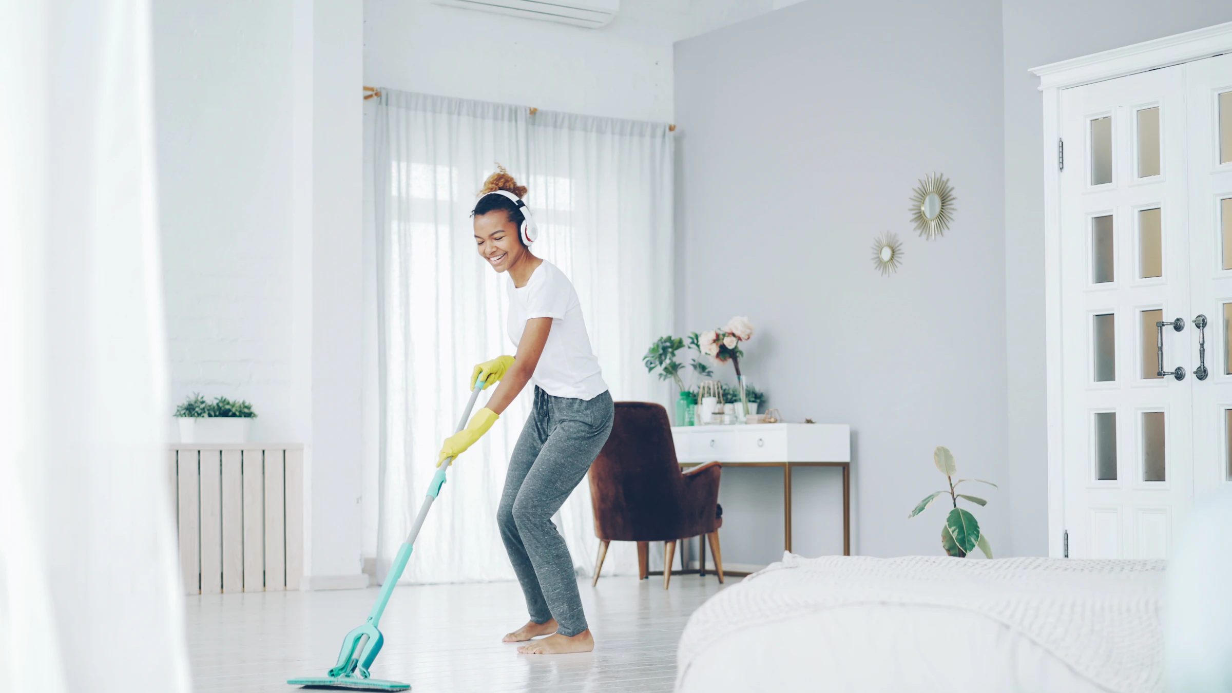 Happy cleaner mopping a sunny room