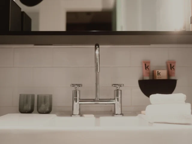 Modern bathroom sink with a chrome tap, glasses and towels