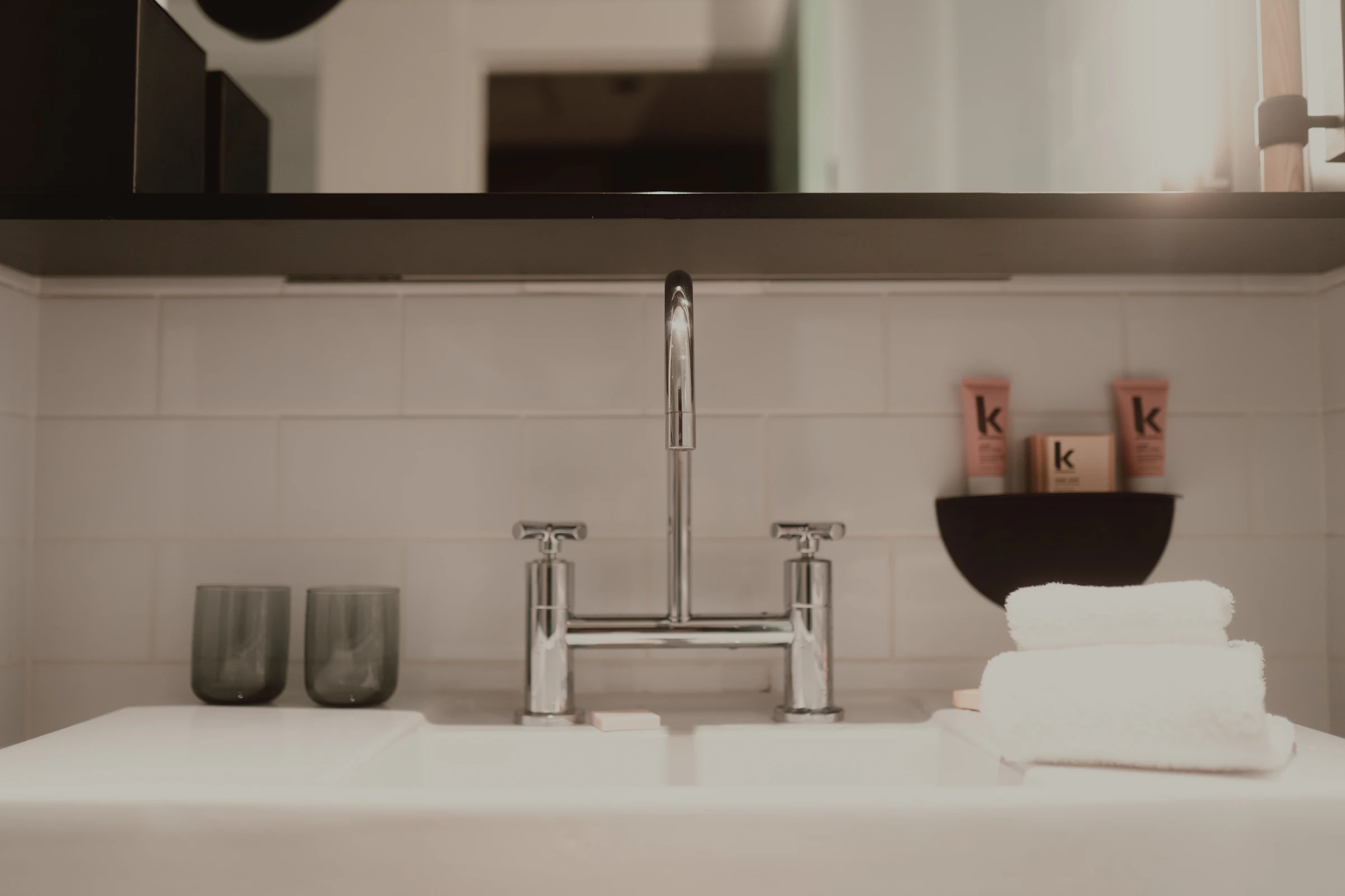 Modern bathroom sink with a chrome tap, glasses and towels