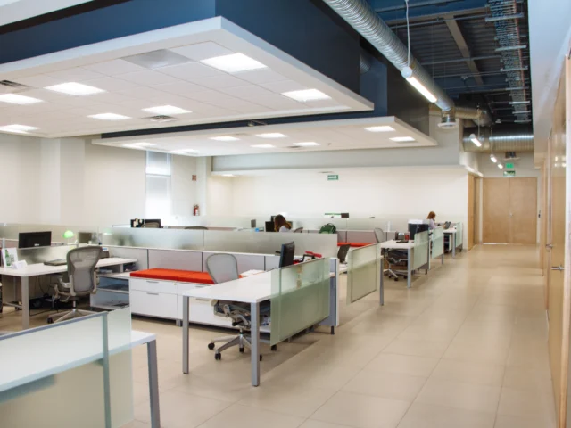 Open plan office with rows of white desks and frosted glass partitions