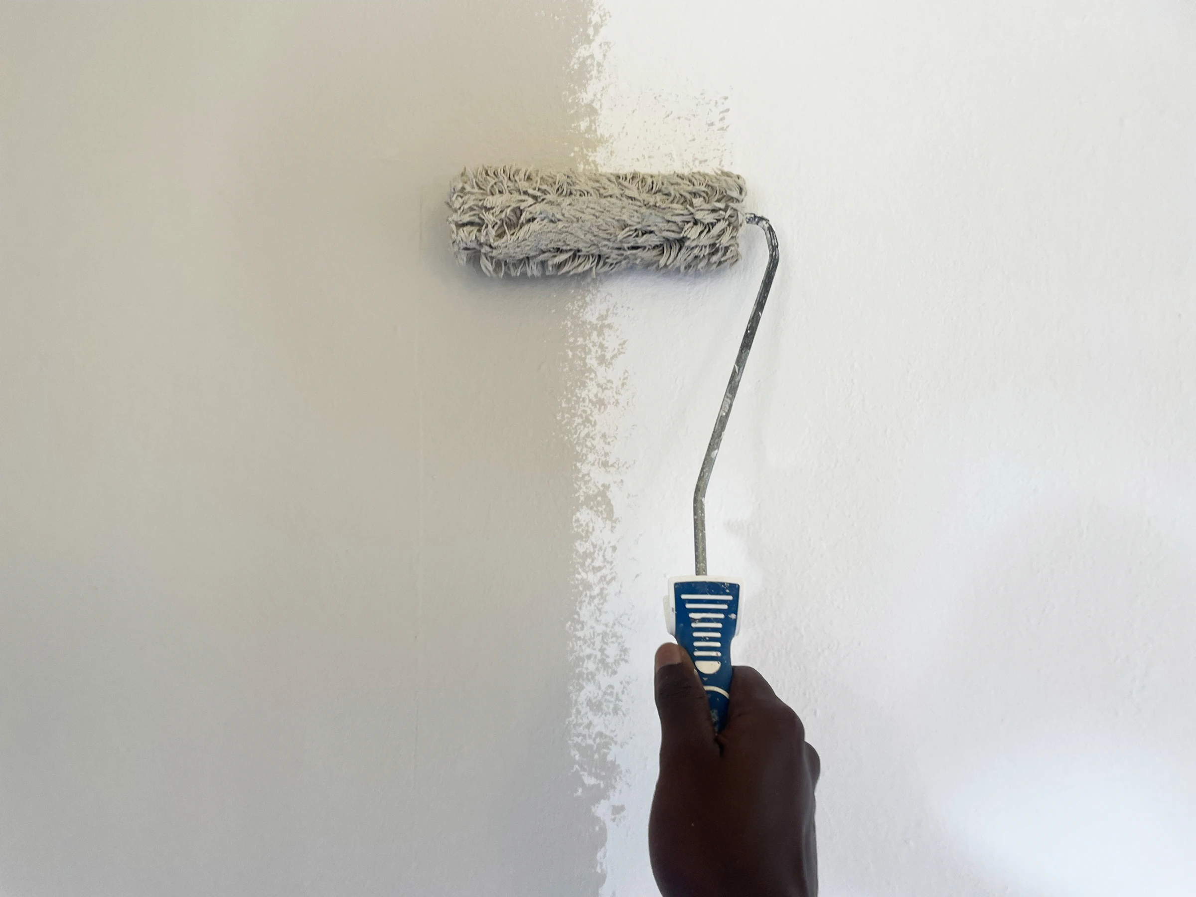Person painting a wall with a paint roller