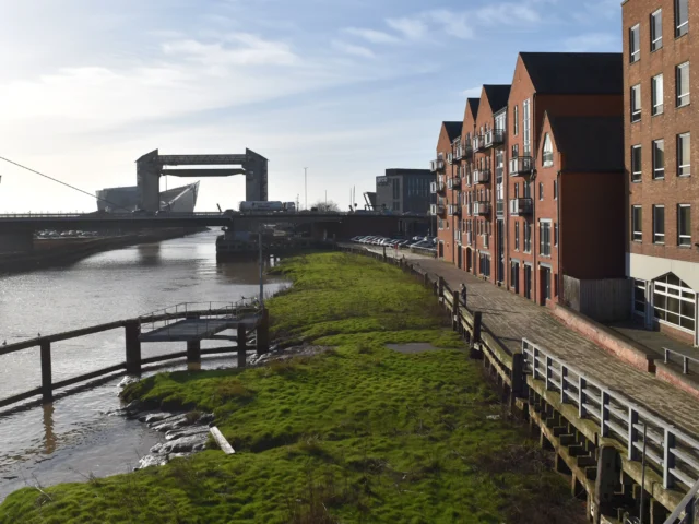Riverside path beside red-brick buildings