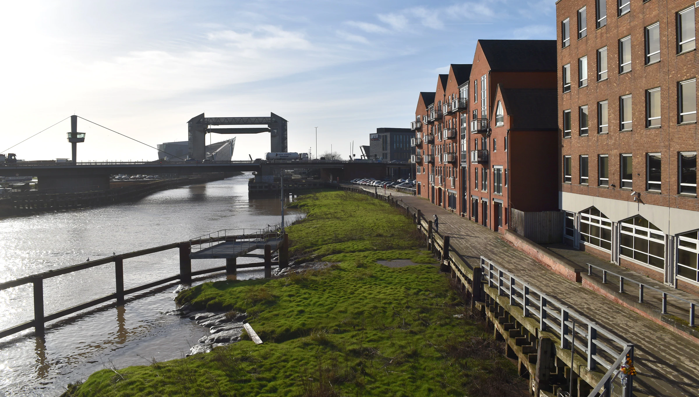 Riverside path beside red-brick buildings