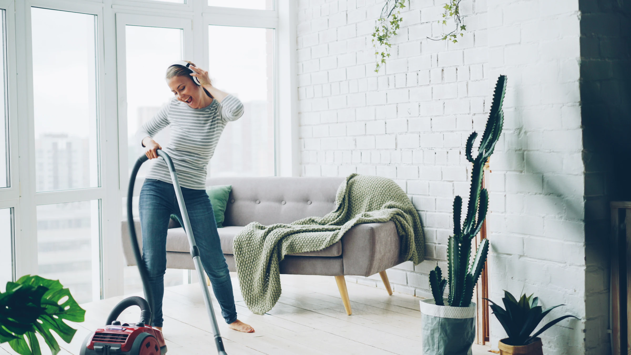 Smiling cleaner vacuuming a bright, modern living room