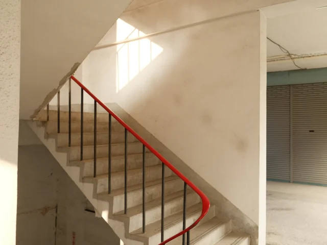 White communal staircase with a red handrail