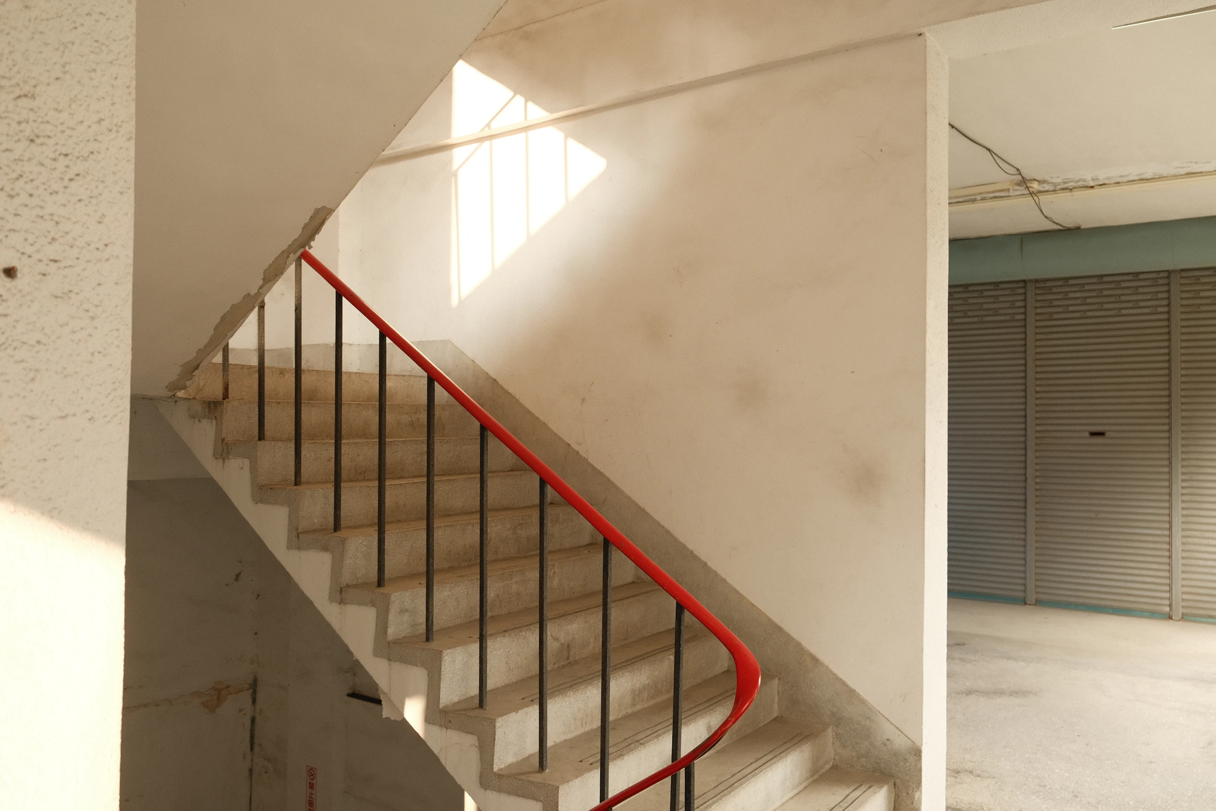White communal staircase with a red handrail