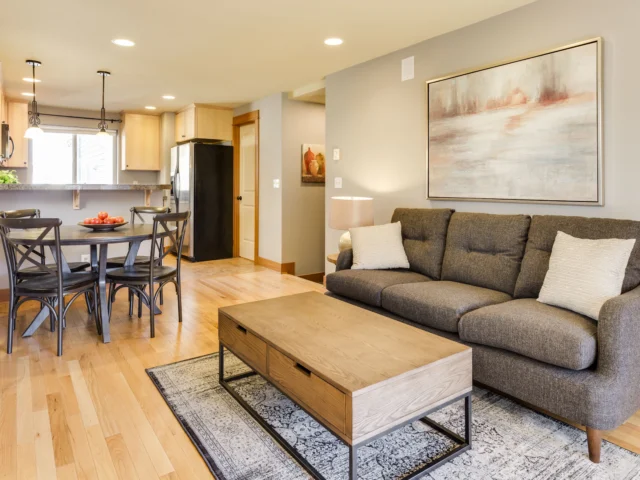 Wooden coffee table and grey three-seat sofa in a finished room